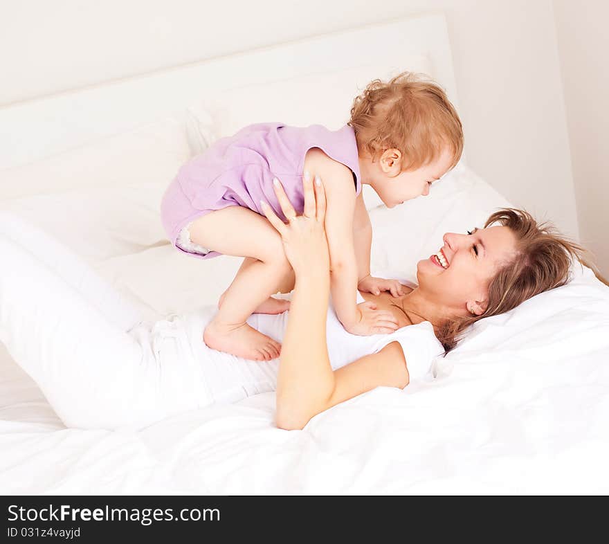 Young beautiful mother and her baby on the bed at home. Young beautiful mother and her baby on the bed at home