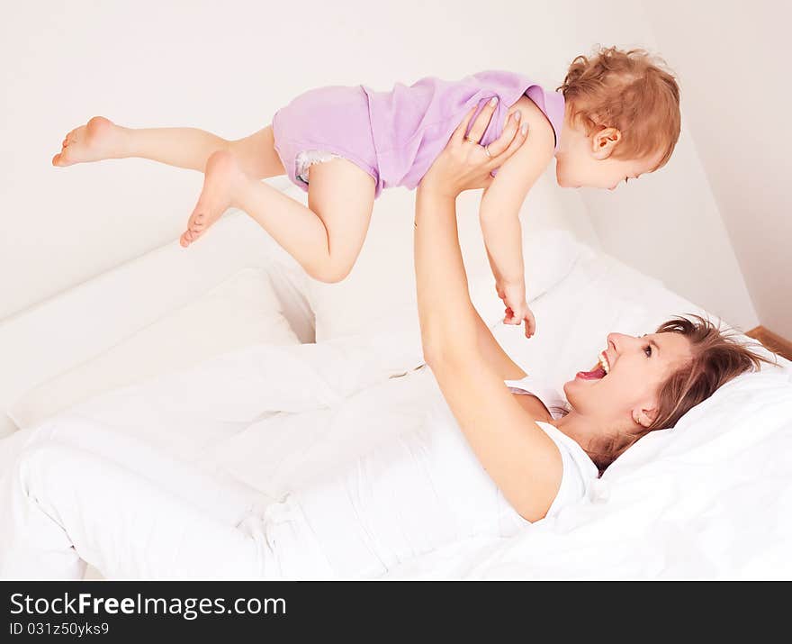 Young beautiful mother and her baby on the bed at home. Young beautiful mother and her baby on the bed at home