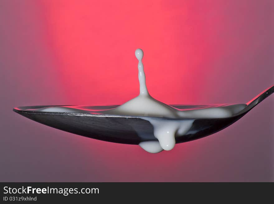 Milk in spoon with red background. Milk in spoon with red background