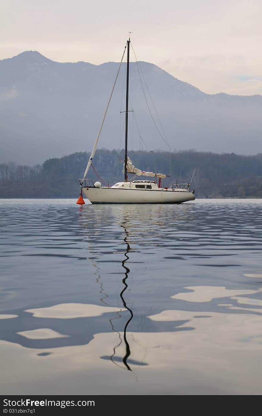 A white sailboat in a lake with mountains in the background