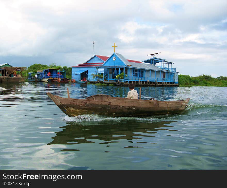 A fisherman's boat cruising in front of a floating church on the Tolen Sap Lake near Siem Reap (Cambodia)