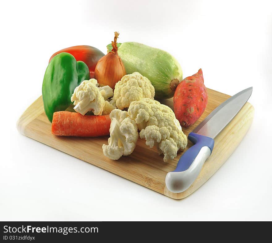 Fresh vegetables on a wooden board made of bamboo and a knife for cutting. Fresh vegetables on a wooden board made of bamboo and a knife for cutting