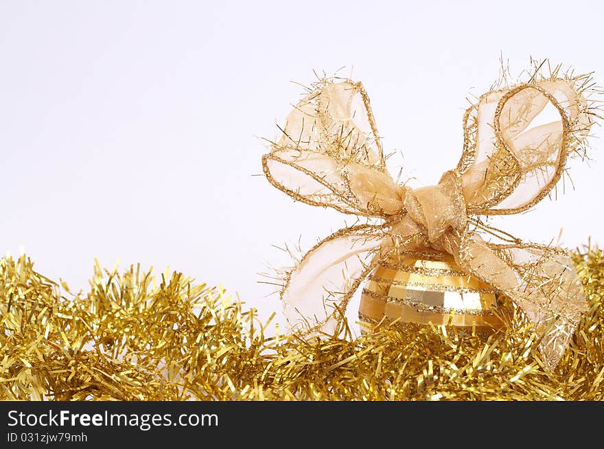 One gold Christmas bauble on yellow tinsel isolated on white background with copy space.