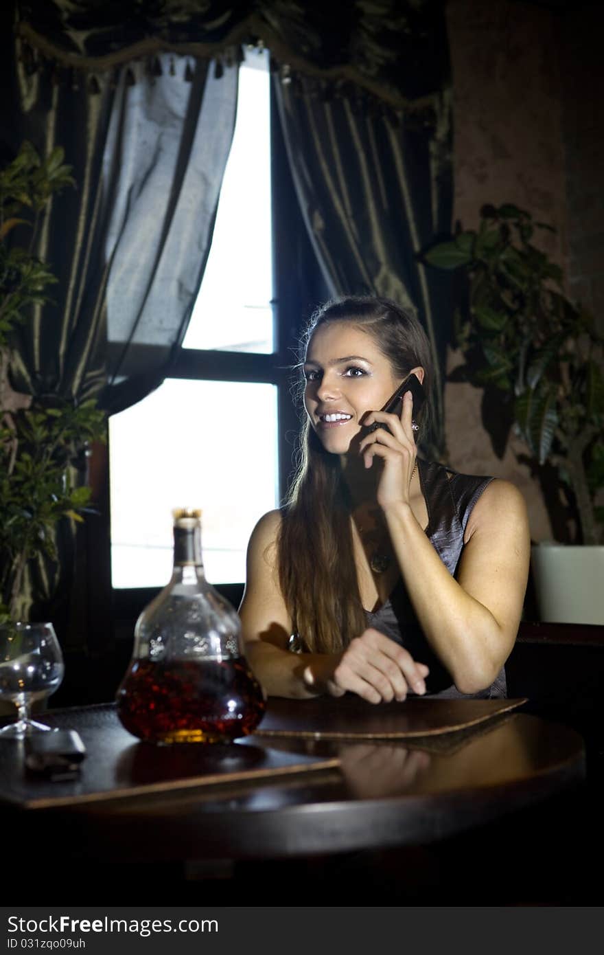 Woman sits at the table and speaks by mobile phone in vintage restaurant. Woman sits at the table and speaks by mobile phone in vintage restaurant