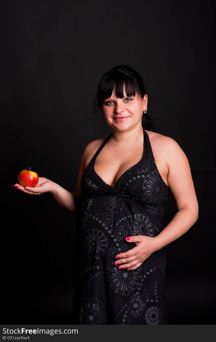 Pregnant woman in black dress with red apple