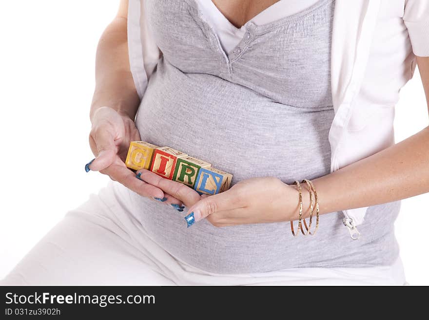 A close up of a woman who is pregnant holding blocks that spell out the word girl. A close up of a woman who is pregnant holding blocks that spell out the word girl.