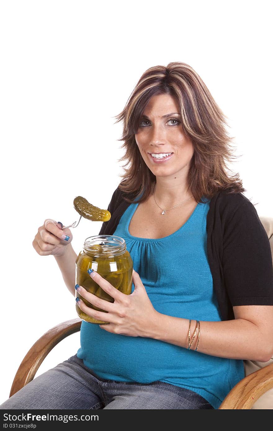 A pregnant woman sitting and getting ready to eat a pickle with a happy expression on her face. A pregnant woman sitting and getting ready to eat a pickle with a happy expression on her face.