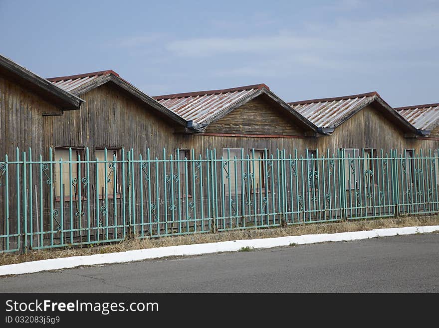 Old wooden baraks behind a green old fence