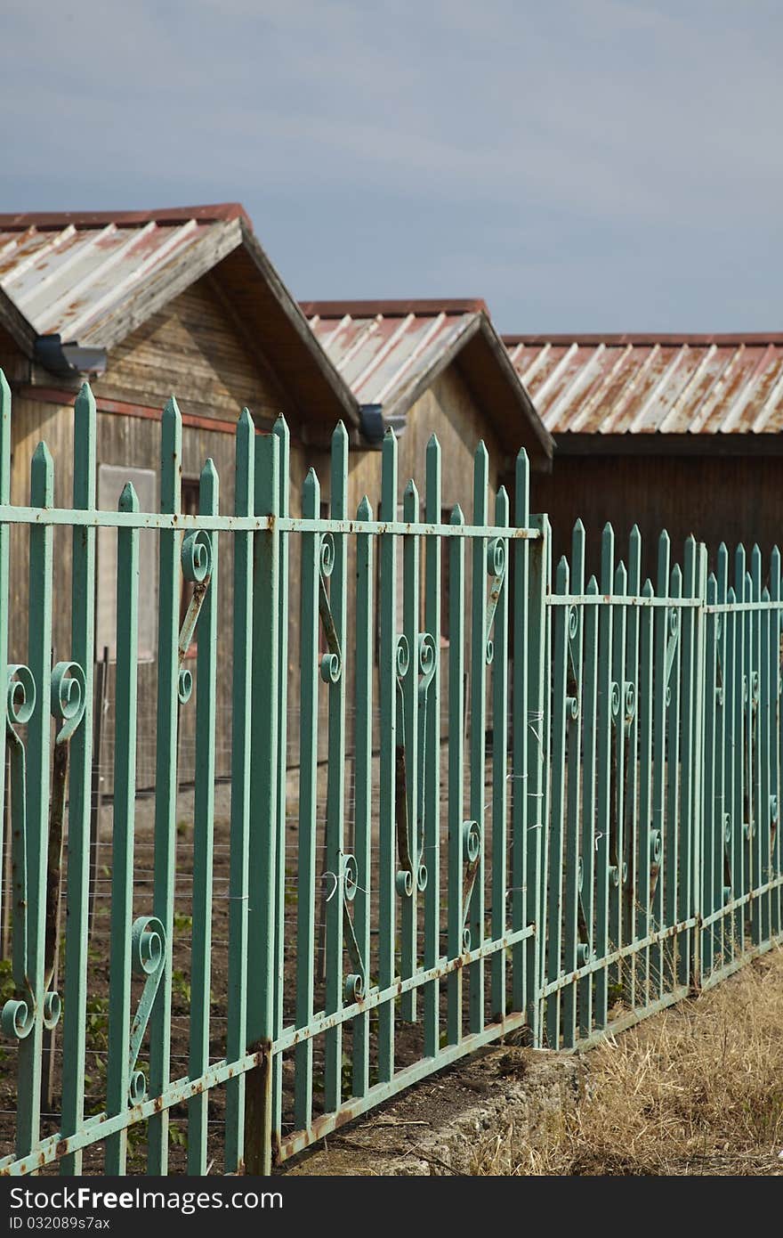 Old wooden baraks behind a green old fence