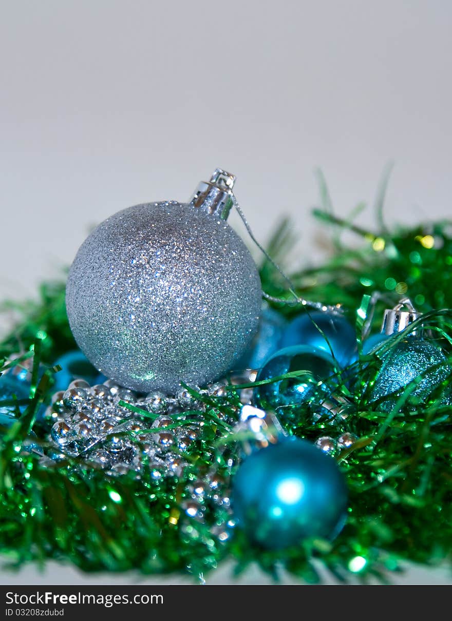 Blue, silver and green Christmas balls laying on the table, white background. Blue, silver and green Christmas balls laying on the table, white background