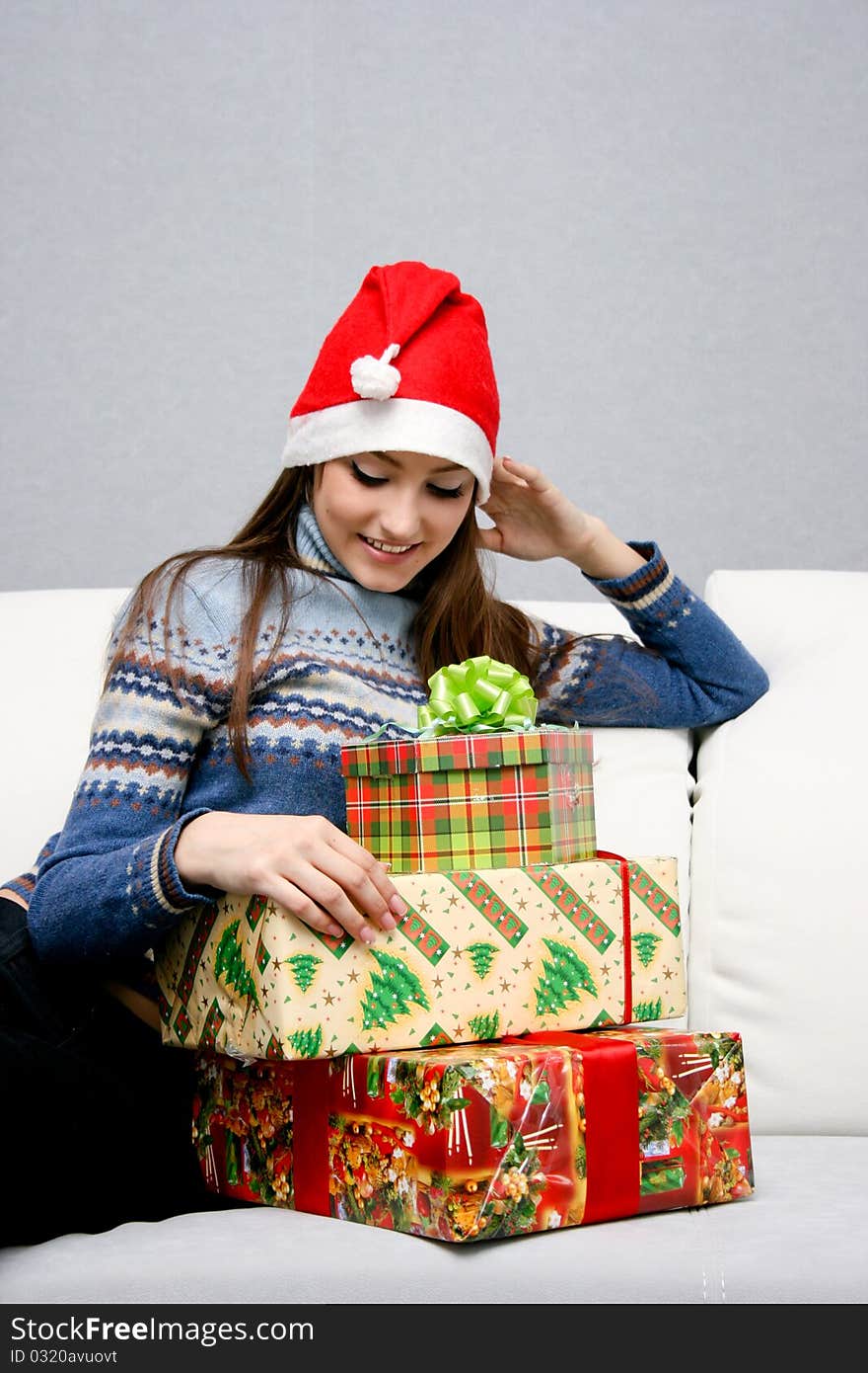 Pretty caucasian girl in santa hat looking at gifts