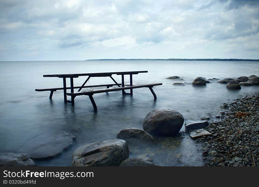 A picnic table half submerged in the lake. A picnic table half submerged in the lake.