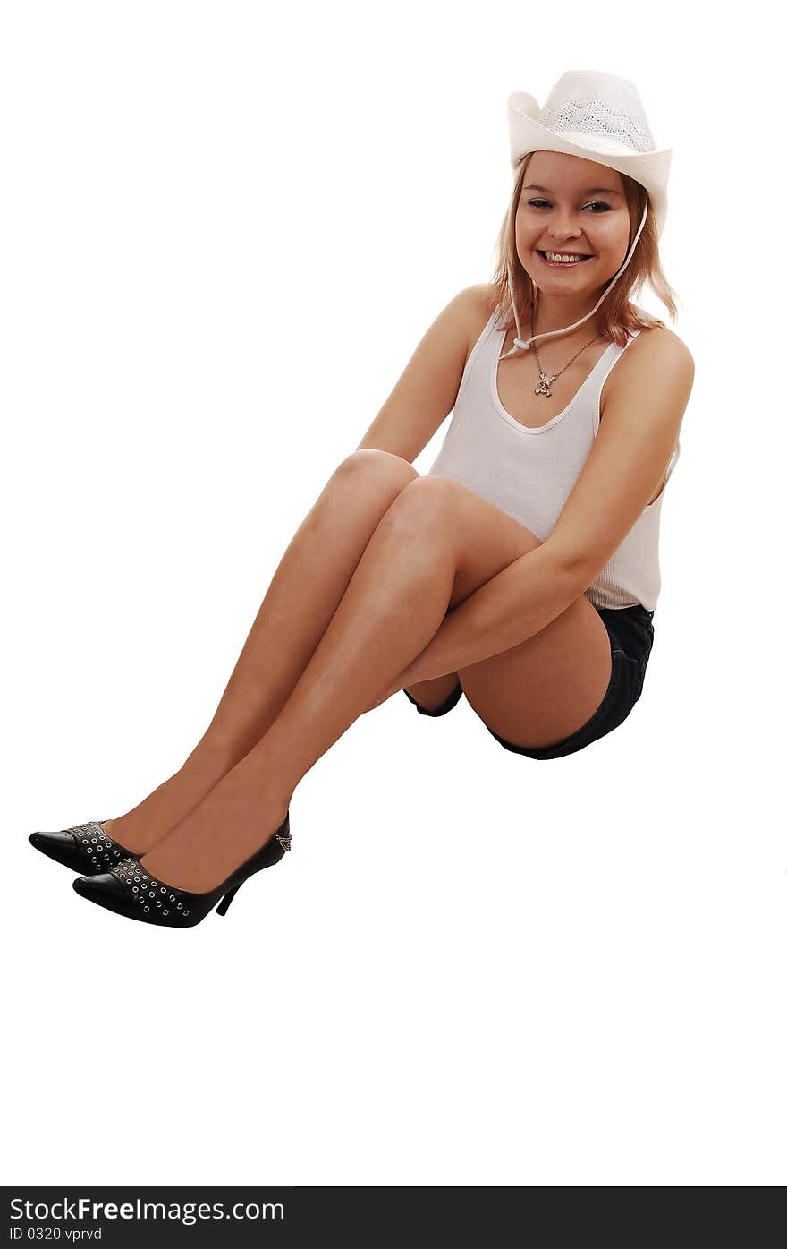 A young woman in shorts and a white undershirt with a white hat sitting on the floor, holding her legs for white background. A young woman in shorts and a white undershirt with a white hat sitting on the floor, holding her legs for white background.