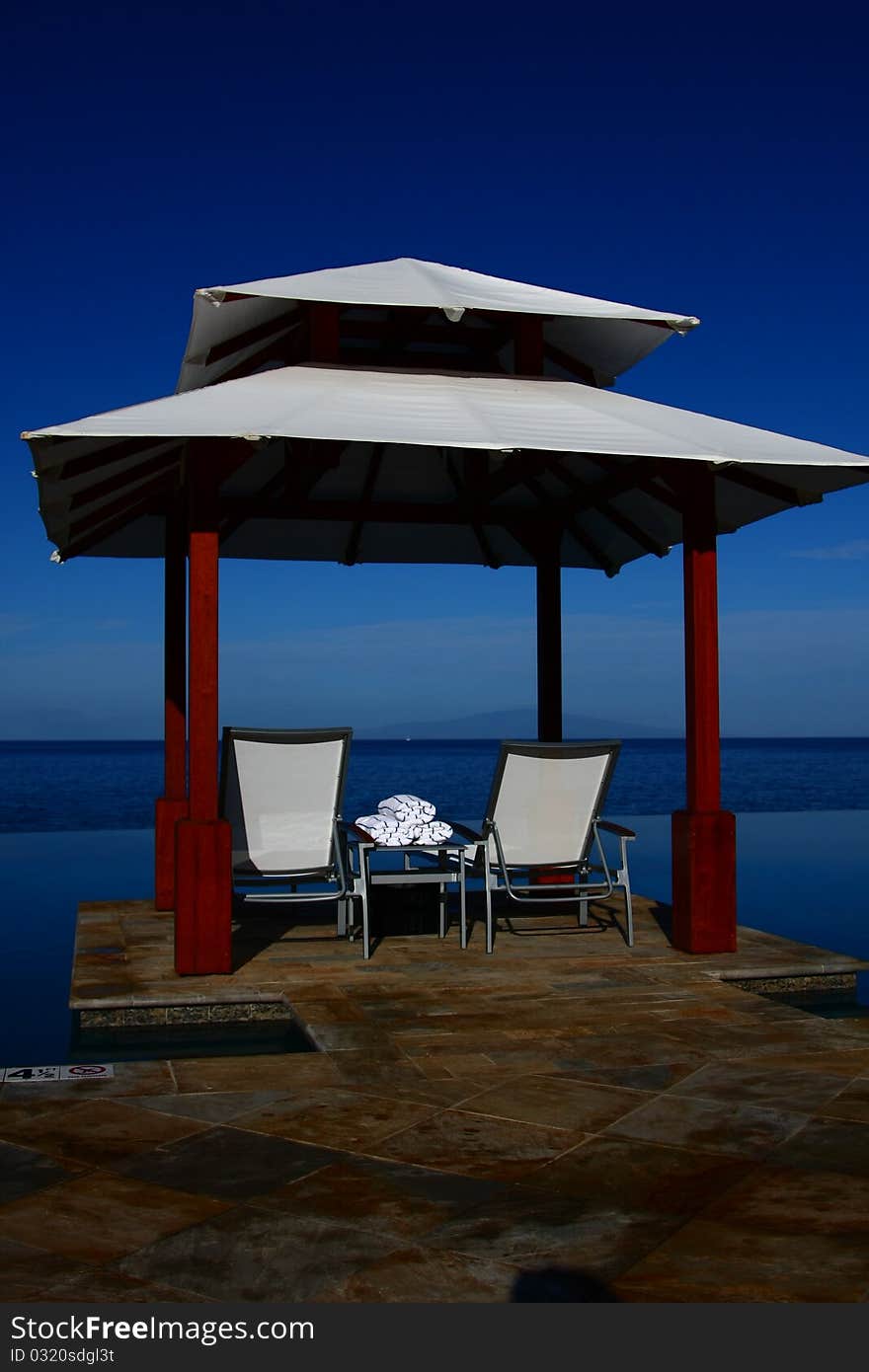 This is a small cabana beside an infinity edge pool near the ocean in Maui.