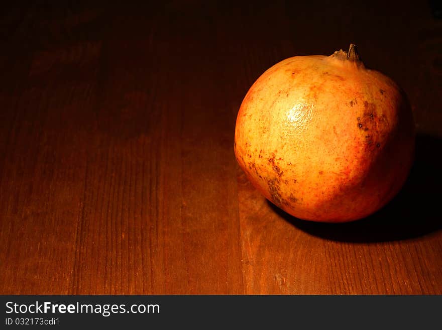 Fresh pomegranate lying on dark wooden background with lighting effect. Fresh pomegranate lying on dark wooden background with lighting effect