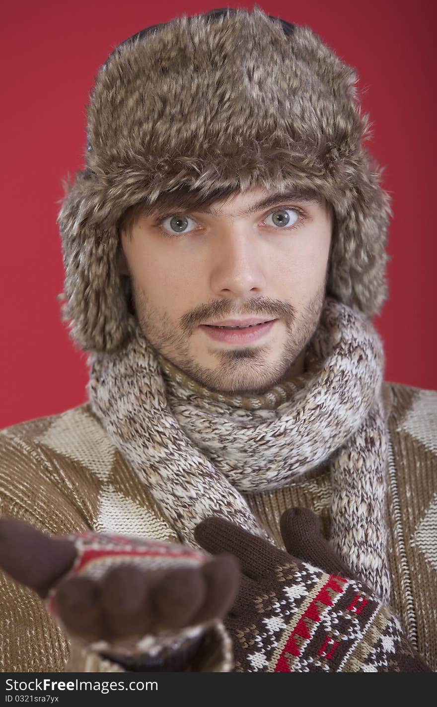 Young man in winter clothes making helping hand gesture