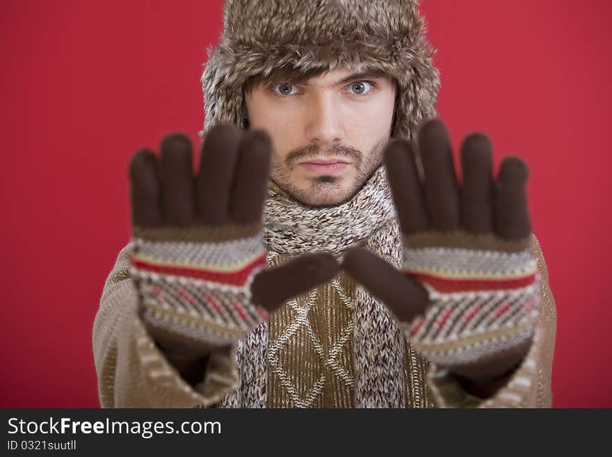 Man in winter clothing making stop hand gesture over red background