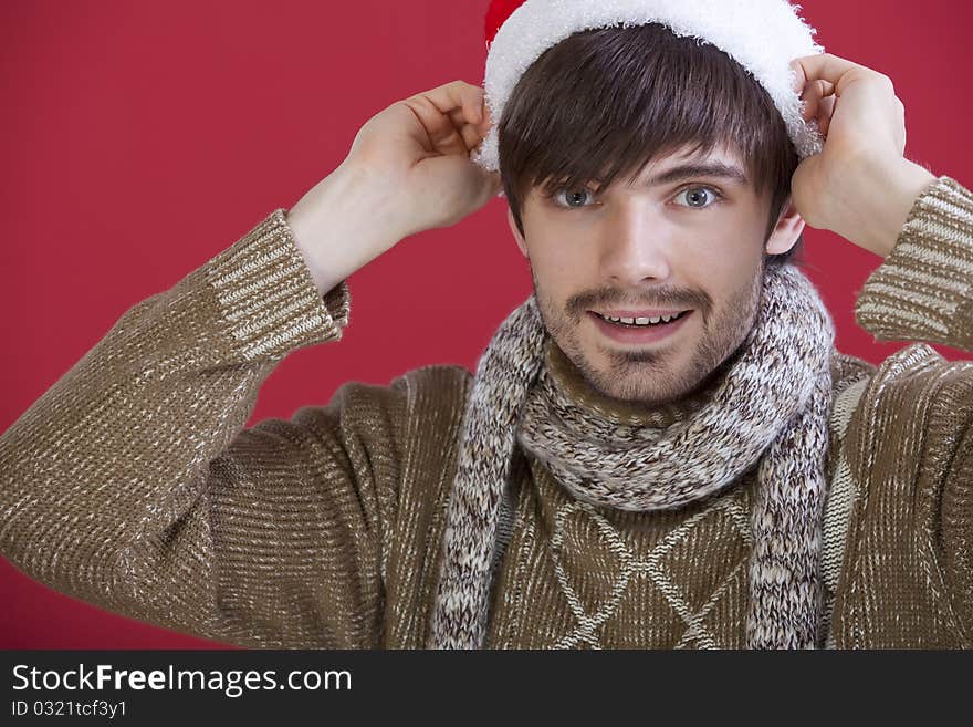 Young happy man in santa hat over red background