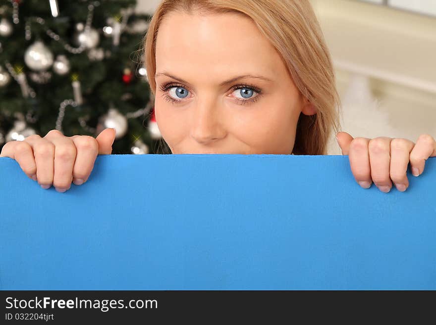 blond angel standing in front of a christmas tree holding a sign. blond angel standing in front of a christmas tree holding a sign