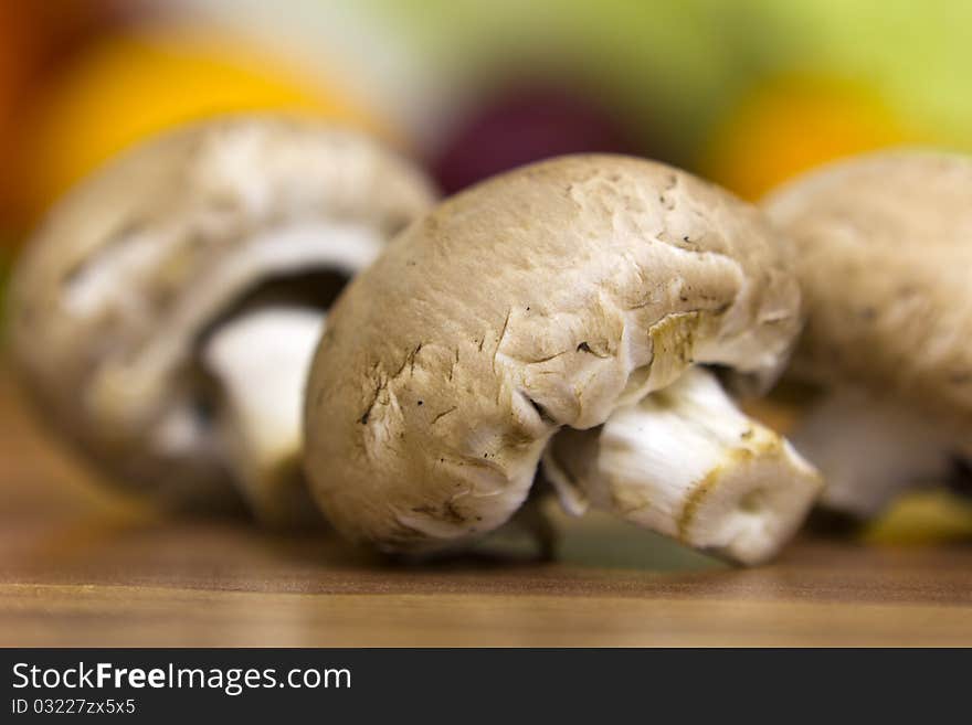 Three brown mushrooms lying on the table, nice colourful bokeh