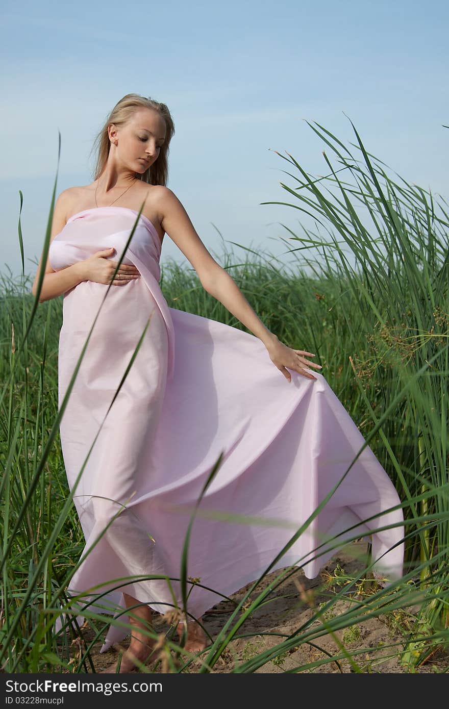 Beautiful pregnant with pink fabric fluttering in the wind. Beautiful pregnant with pink fabric fluttering in the wind