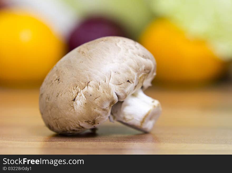 One brown mushroom lying on the table, nice colourful bokeh