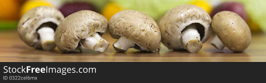 Five brown mushrooms lying on the table, nice colourful bokeh