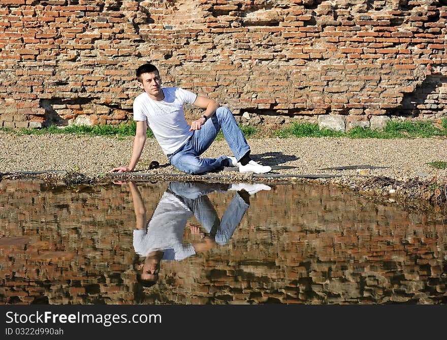 Portrait of an young man thinking, sitting near a lake. Portrait of an young man thinking, sitting near a lake