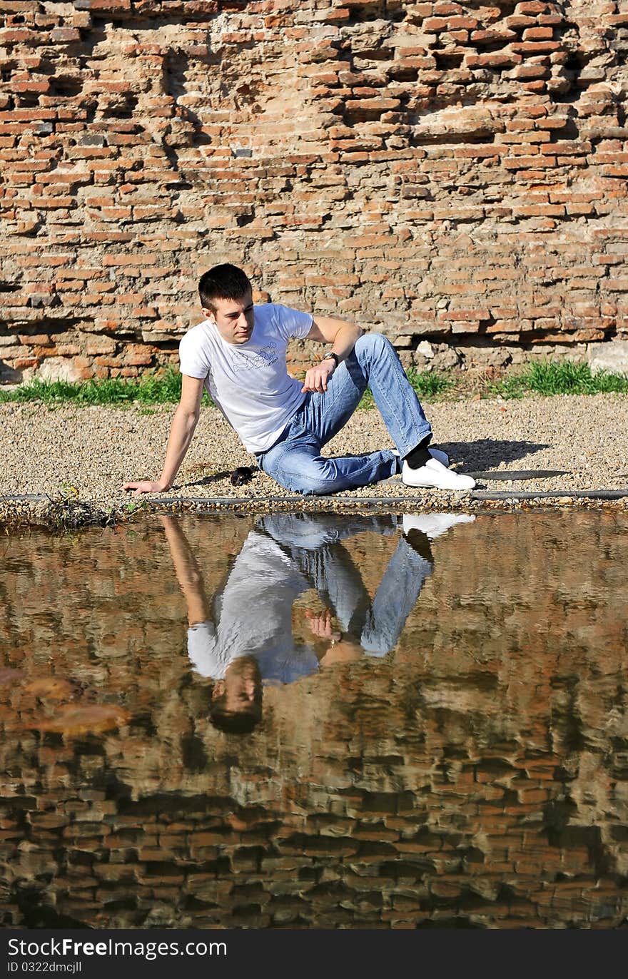 Portrait of an young man thinking, sitting near a lake. Portrait of an young man thinking, sitting near a lake