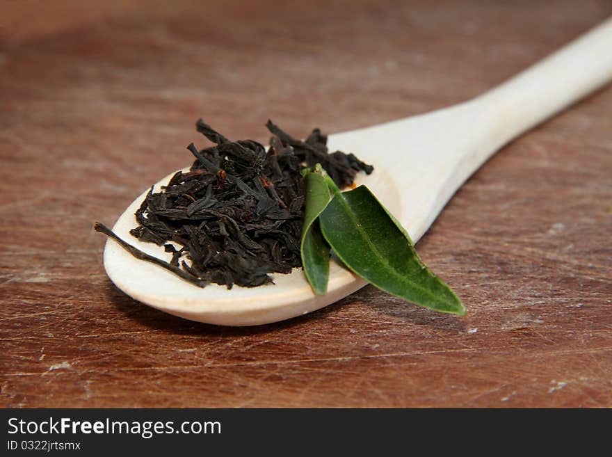 Black tea on spoon over a wooden texture. Black tea on spoon over a wooden texture