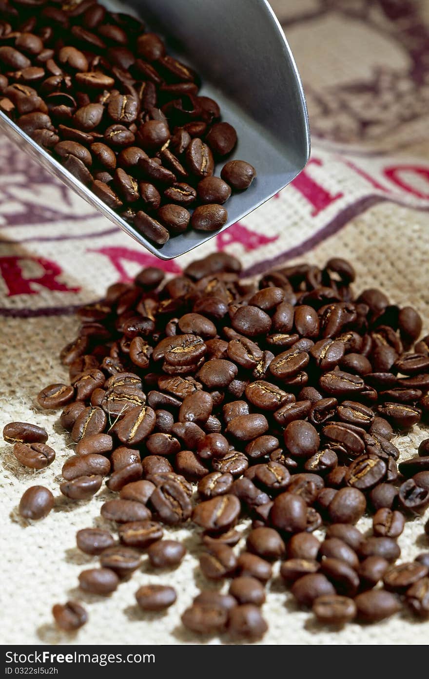 Roasted coffee beans on a spoon and table.