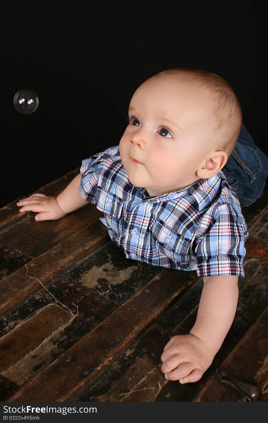 Cute little boy on an antique trunk wearing blue jeans. Cute little boy on an antique trunk wearing blue jeans