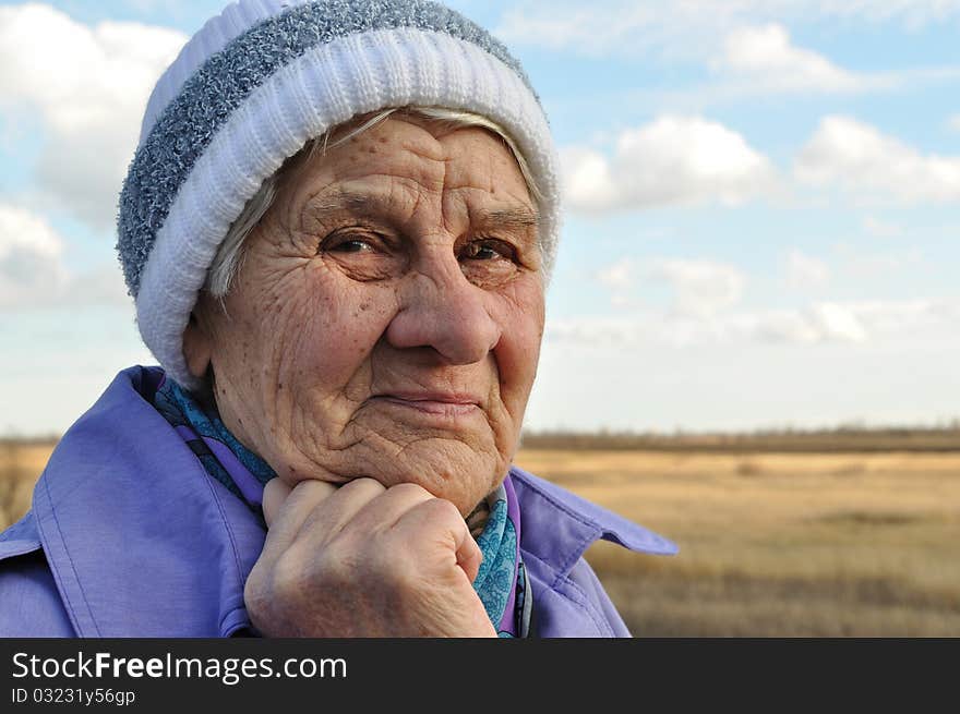 Reflecting, an elderly woman looks away, the background road, autumn