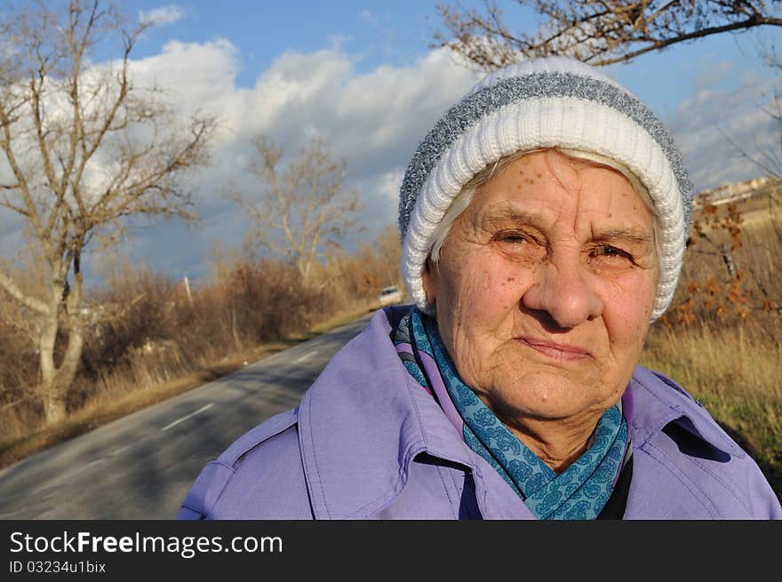 Reflecting an elderly woman in glasses, looks at the camera, the background road, autumn