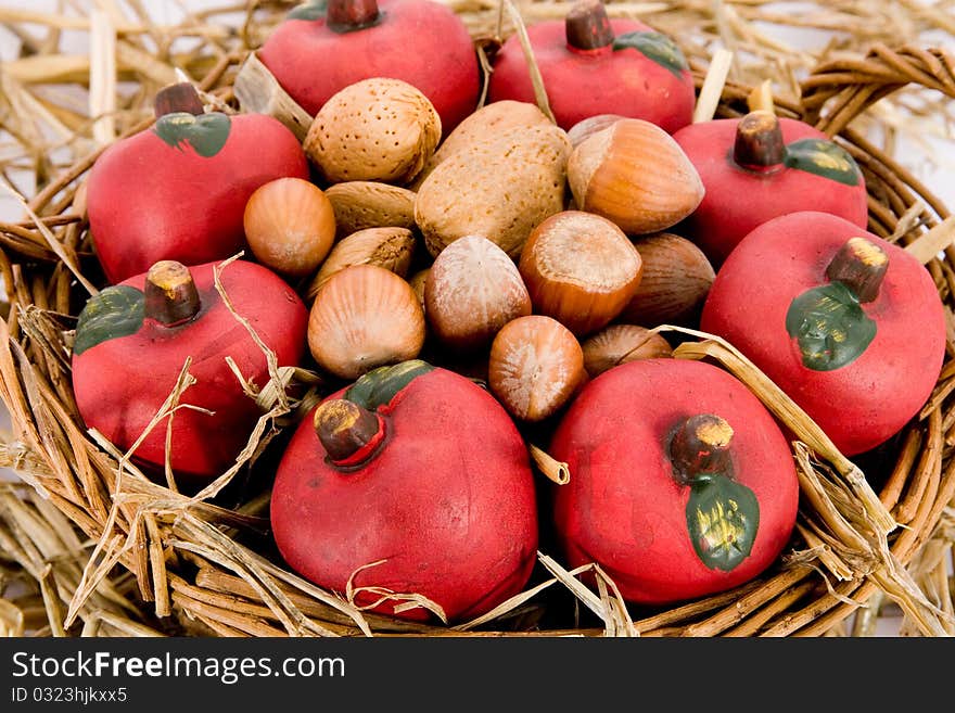 Closeup of red apples made of clay and nuts in a basket with straw. Closeup of red apples made of clay and nuts in a basket with straw