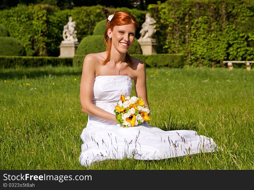 Portrait of young bride at the garden sitting on grass. Portrait of young bride at the garden sitting on grass.