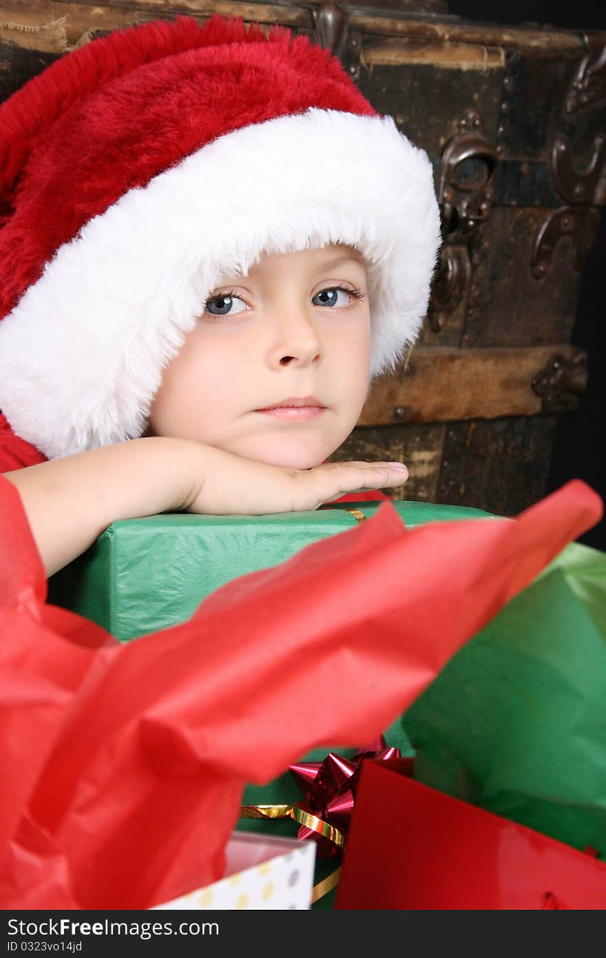 Beautiful boy wearing a christmas hat waiting to open presents. Beautiful boy wearing a christmas hat waiting to open presents