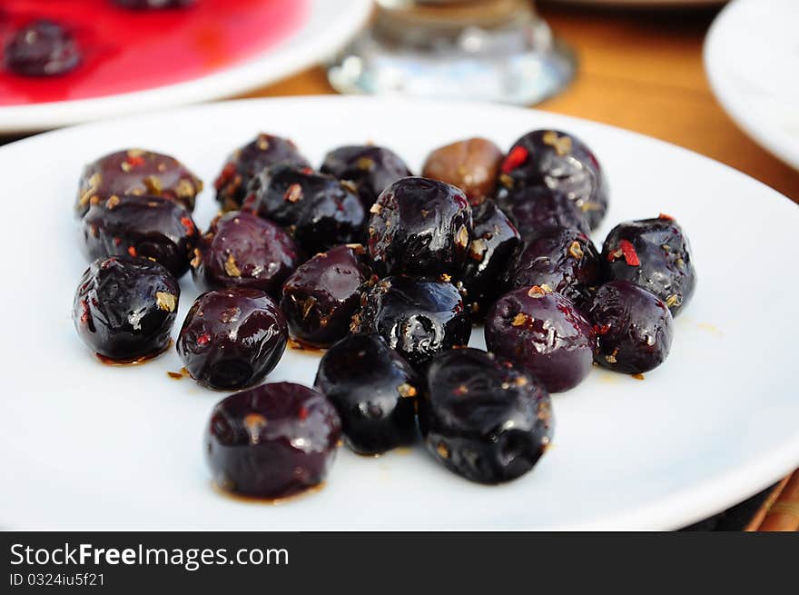 Black ripe olives on a white plate on table. Black ripe olives on a white plate on table