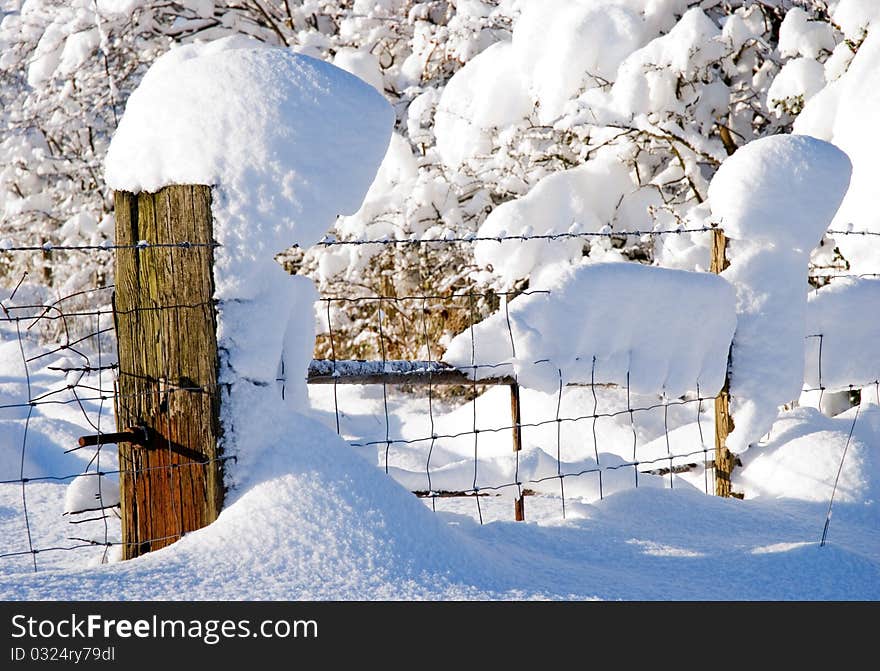 A horizontal image of snow drifts and snow covered fences in bright sunlight. A horizontal image of snow drifts and snow covered fences in bright sunlight