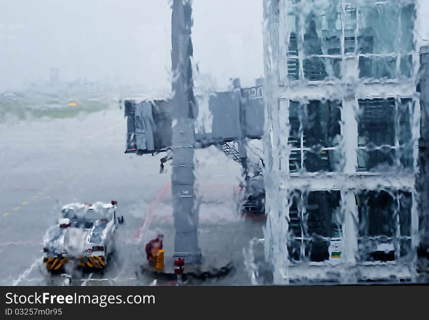 Boring rain taken through airport window; focus on the window covered by water streams. Boring rain taken through airport window; focus on the window covered by water streams