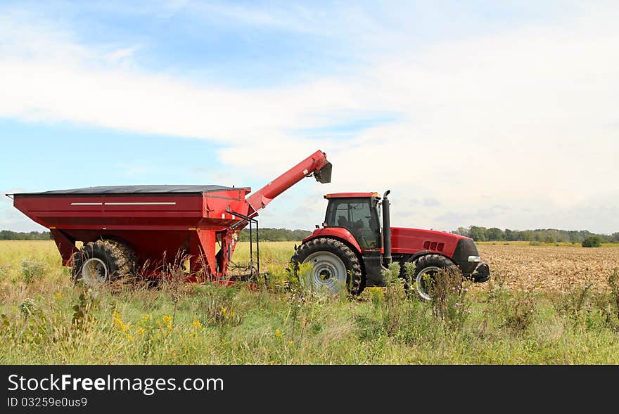 Red farm tractor and wagon in a farm field