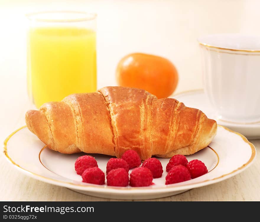 Breakfast. A cup of coffee, croissant, orange juice and berries