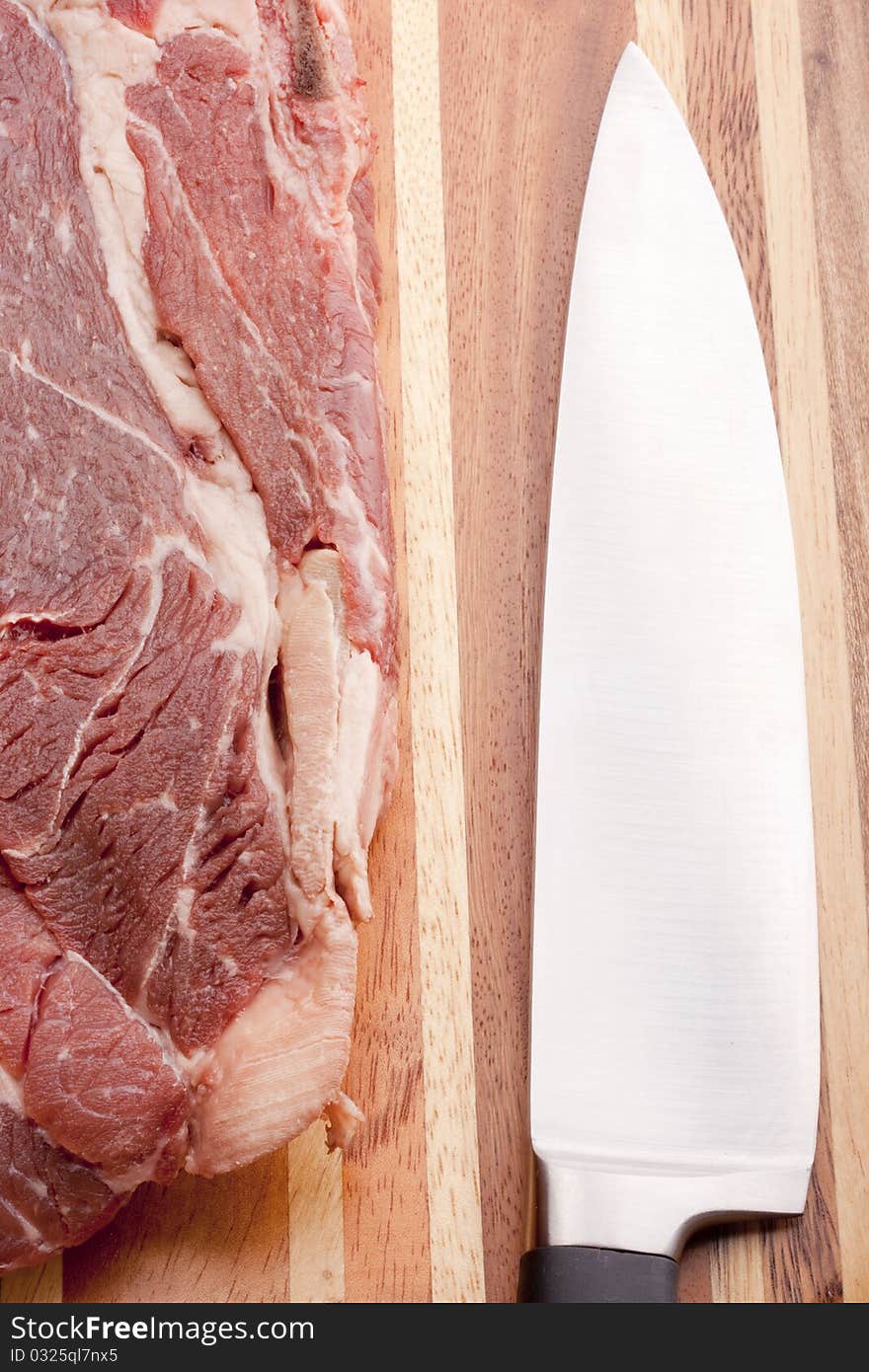 A piece of raw meat on a multilayer wooden kitchen cutting board.