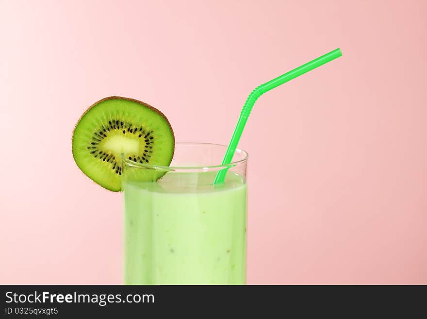 Kiwi juice in a glass on a pink background