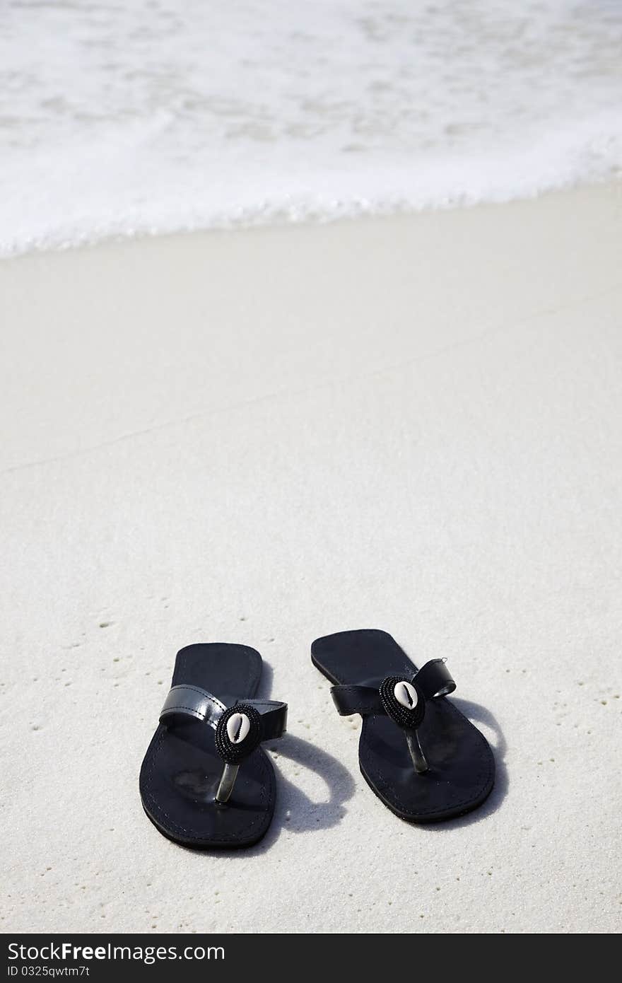 Black flip flops on the beach