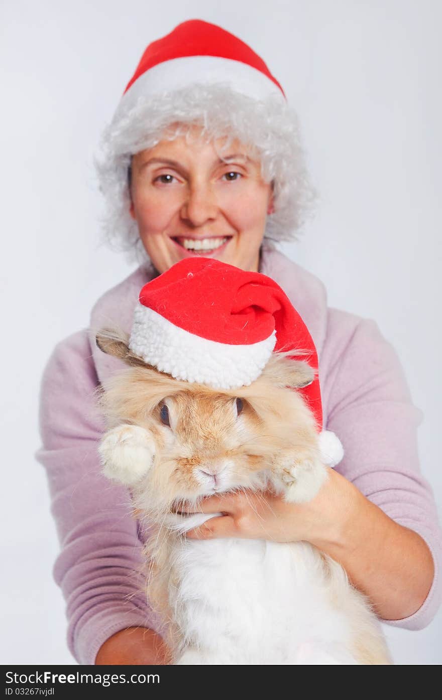 Pretty young woman in Santa hat holding cute rabbit. Focus on the rabbit.