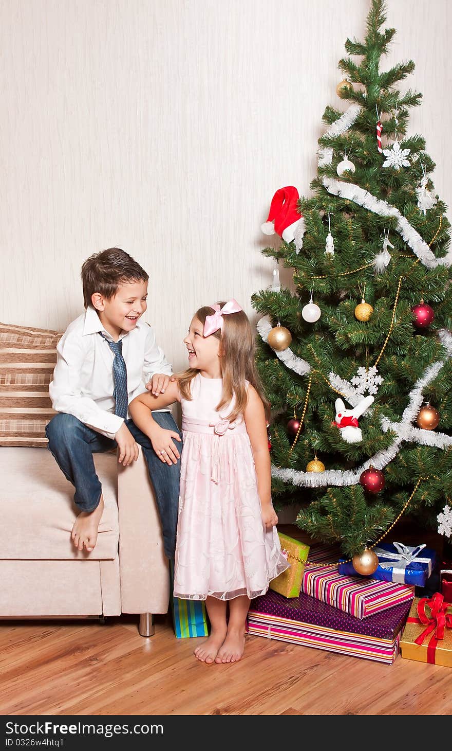 Merry girl and boy with gifts near a new-year tree. Merry girl and boy with gifts near a new-year tree