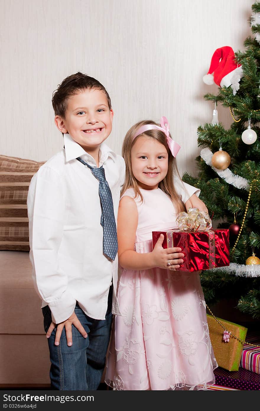 Merry girl and boy with gifts near a new-year tree. Merry girl and boy with gifts near a new-year tree