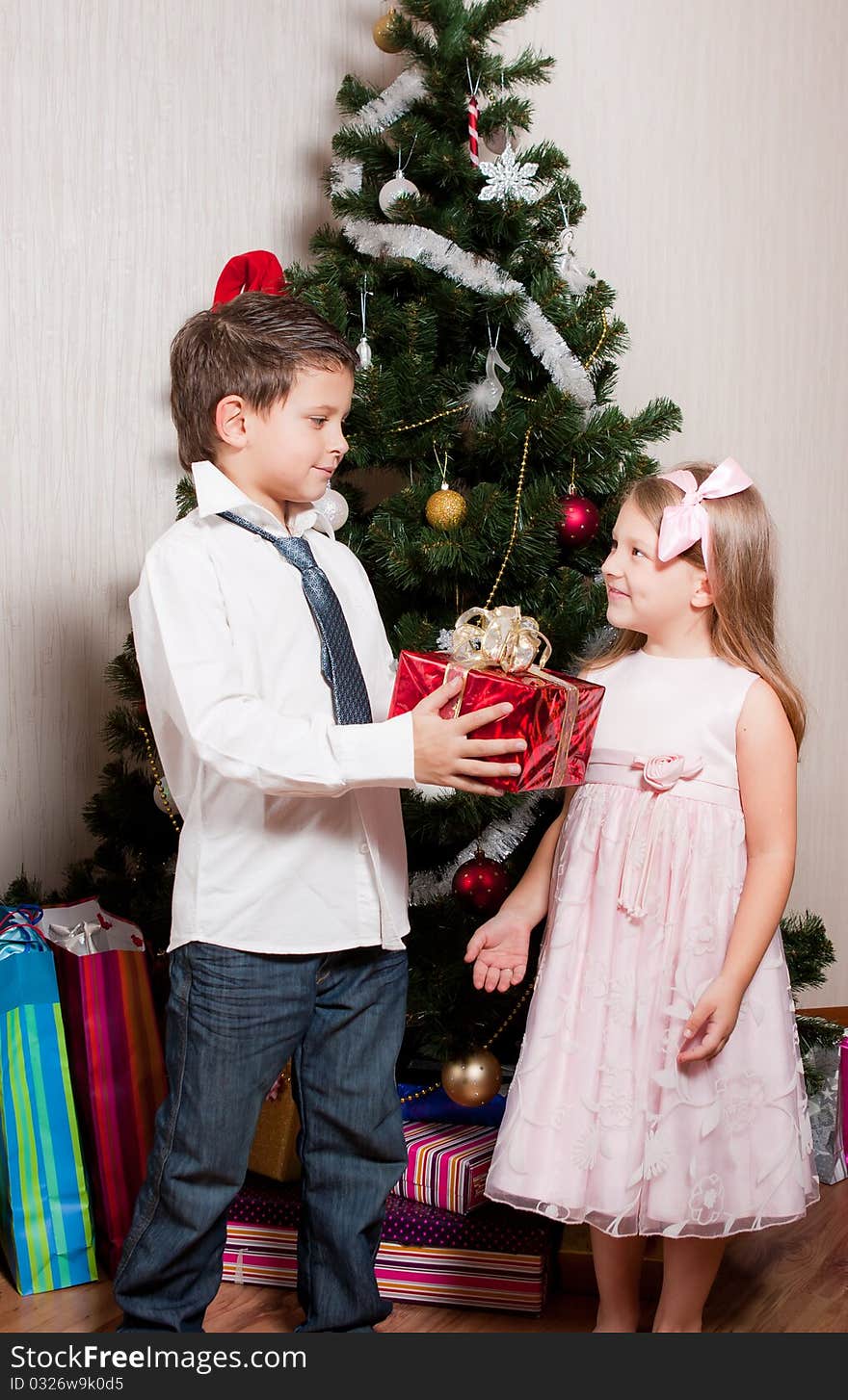 Merry girl and boy with gifts near a new-year tree. Merry girl and boy with gifts near a new-year tree