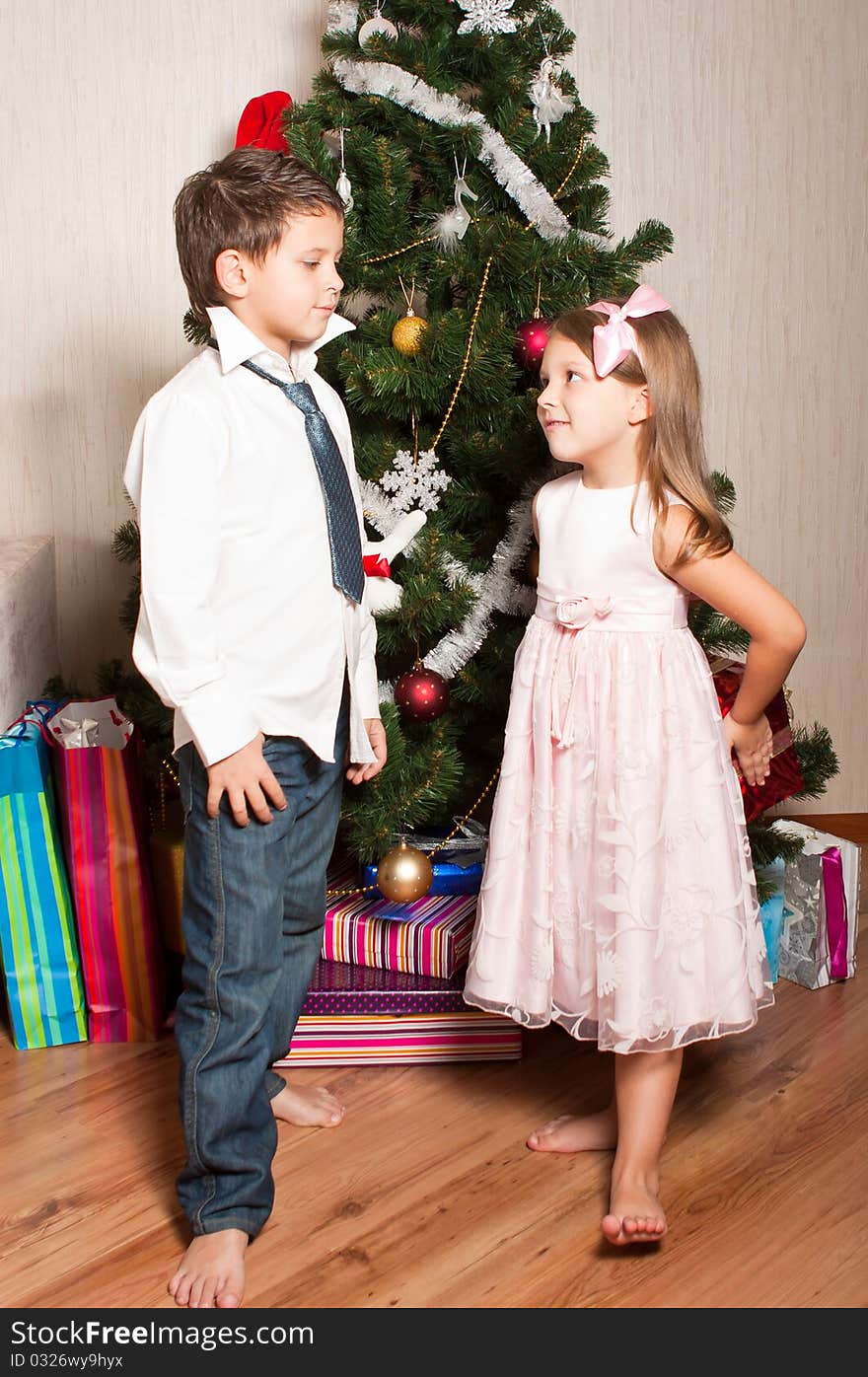 Merry girl and boy with gifts near a new-year tree. Merry girl and boy with gifts near a new-year tree